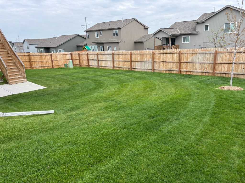 A photo of a customer's lawn showcasing a curved stripe pattern in cut in the grass